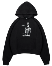 Ein schwarzer Hoodie von der Marke Strides mit einem weißen Gesticke auf der Vorderseite (zentral). Der Aufdruck zeigt eine Figur und einen "strides" Schriftzug.